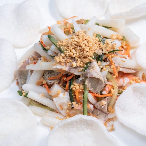 Vietnamese lotus root salad with pork, shrimp, vegetables, peanuts, and crispy rice crackers.