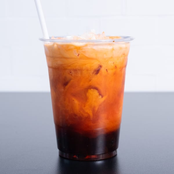 Vietnamese iced coffee with condensed milk and ice in a clear plastic cup with a straw.