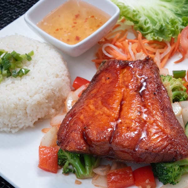 Vietnamese caramelized fish with rice, vegetables, and a side of dipping sauce.
