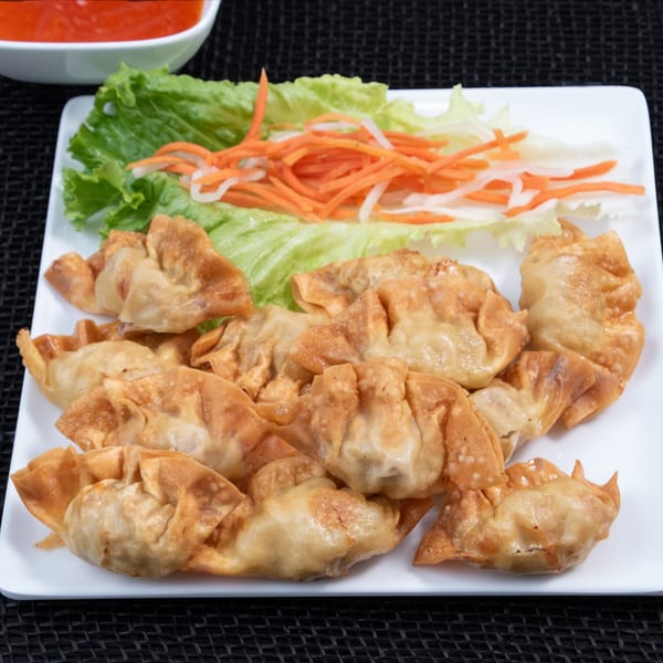Crispy fried wontons with a side of fresh lettuce, shredded carrots, and daikon, served with dipping sauce.