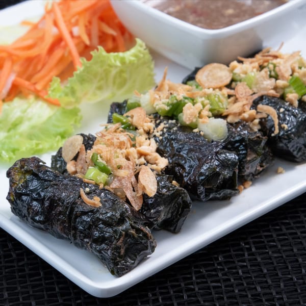 Vietnamese grilled pork sausage wrapped in wild betel leaf, garnished with fried shallots and scallions.