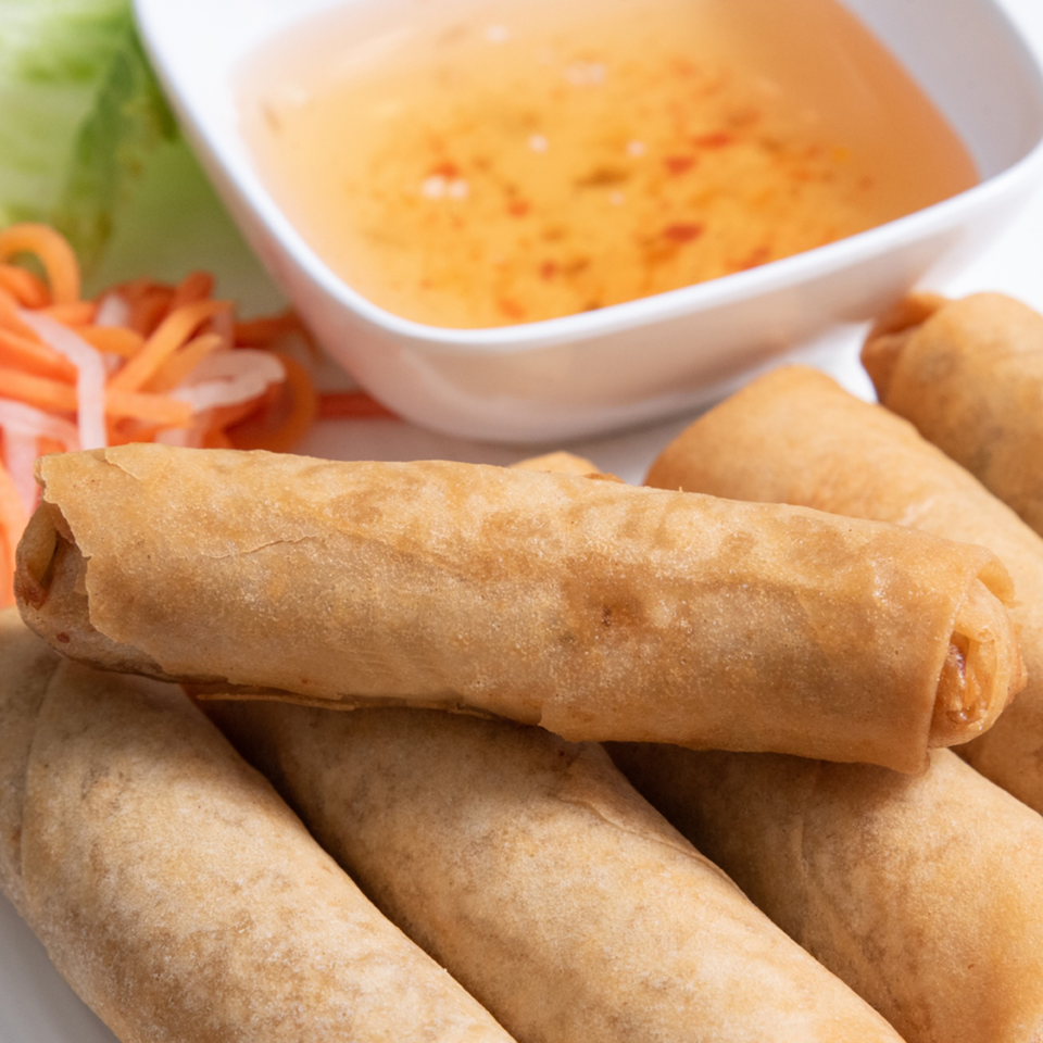 Crispy Vietnamese spring rolls with a side of dipping sauce and pickled vegetables.