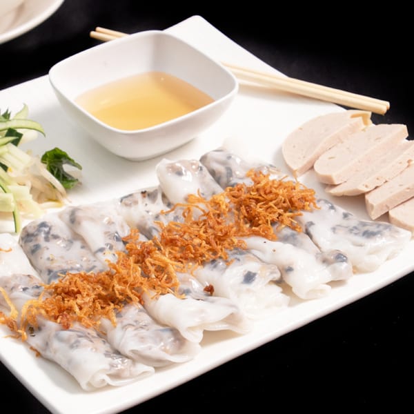 Vietnamese Banh Cuon rice rolls topped with crispy fried shallots, served with dipping sauce and sliced pork.