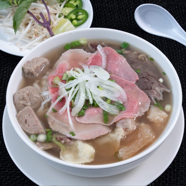A bowl of Phở Skyline's Vietnamese pho with various cuts of beef, onions, and herbs.
